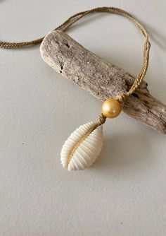 Hawaiian endemic cowrie shell (Granulated Cowrie) paired with a gold freshwater pearl on braided waxed twine. 19 inch cord and fitted with a puka shell closure. The braided waxed twine chain is durable and can be worn in the ocean as well as in other active pursuits! Adjustable Shell Cord Jewelry, Shell Jewelry With Adjustable Cord As Gift, White Necklace With Adjustable Waxed Cord, Gold Sliding Knot Jewelry For Vacation, Shell-shaped Jewelry With Adjustable Cord As Gift, Cream Shell Necklace For Beach, Bohemian Shell With Adjustable Cord As Gift, White Shell Necklace With Adjustable Cord As Gift, Adjustable Cream Shell Necklace For Beach