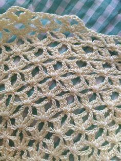 the crocheted doily is on top of a green and white checkered table cloth