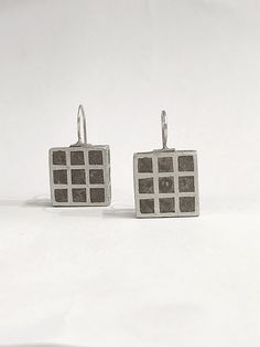 "These geometric dangle earrings are a stunning piece of architectural jewelry. They are made of 925 silver, they have a wide square surface which is perforated with square blanks and it is covered with gray concrete, the finish is rough matte. The unique design of these earrings creates a bold and modern look that is sure to turn heads. DESCRIPTIONS and MEASUREMENTS: Material: Sterling silver. Surface: Concrete. Dimensions : 1,1x1,1 (cm) 0,43x0,43 (in)\", thickness:0,4 (cm) 0,16 (in)\" Total Length  : 5,1(cm) 2,0 (in)\". SEE MORE CONCRETE JEWELRY HERE: www.etsy.com/shop/ArtisJewels?ref=seller-platform-mcnav§ion_id=36353295 ΑLSO COMBINED WITH : www.etsy.com/shop/ArtisJewels?ref=seller-platform-mcnav&search_query=C5 Visit my Etsy shop, ArtisJewels, to see more earrings and jewelry and other Concrete Earrings, Earrings Industrial, Architectural Earrings, Industrial Earrings, Architectural Jewelry, Gray Concrete, Concrete Jewelry, Earrings Geometric, Square Earrings