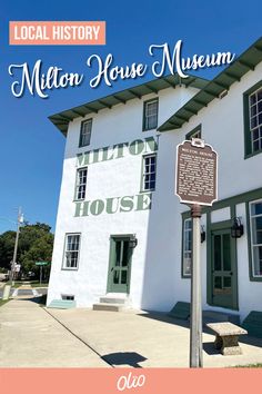 a sign in front of a white building with green shutters and the words mill house museum on it