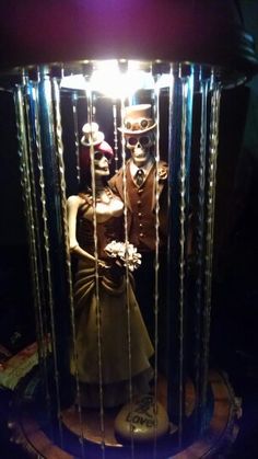 a statue in the shape of a man and woman inside a cage with lights on