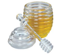 a glass honey jar with a wooden spoon next to it