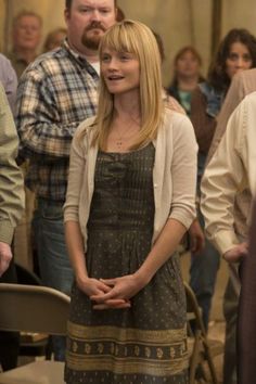 a woman standing in front of a group of people with her hands on her hips