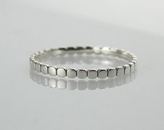 a white gold ring with small squares in the middle, set on a plain surface