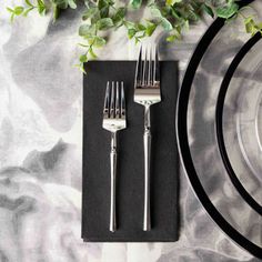 a place setting with silverware and greenery