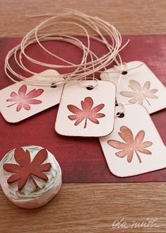 four tags with leaves on them are sitting on a table next to a bottle opener