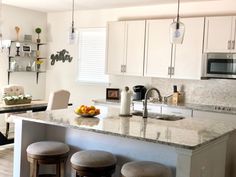 a kitchen with an island and stools in front of the counter top, next to a sink