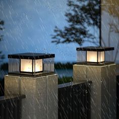 two lanterns sitting on top of cement pillars in the rain