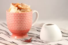 a cup with some food in it next to a teapot and spoon on a table