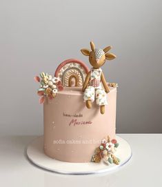 a pink cake with a deer decoration on top