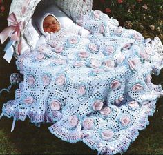 a baby is laying in a basket on the grass with a crocheted blanket