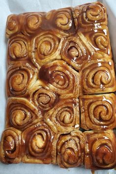 cinnamon rolls sitting on top of each other in a baking pan with caramel glaze