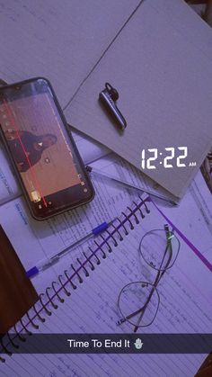 a cell phone sitting on top of a notebook next to a pen and eyeglasses