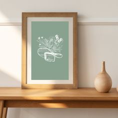 a wooden table with a vase and some flowers on it next to a framed photograph