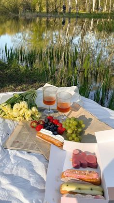 a picnic table with food and drinks on it next to a lake in the woods