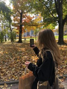 a woman sitting on the ground with her cell phone in her hand and looking at it