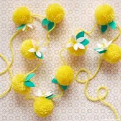 four yellow pom - poms with green leaves and white flowers