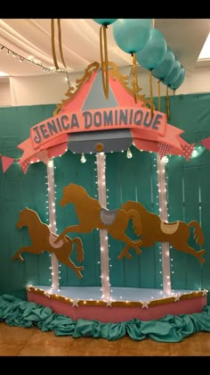 a merry go round with horses and balloons hanging from it's sides in a room