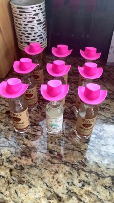 six bottles with pink hats on them sitting on a counter