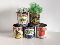 four tins with plants in them sitting on a table