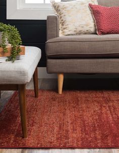 a living room scene with focus on the couch and chair, which has a red area rug