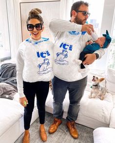 a man and woman in matching shirts holding a baby