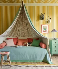 a bed with a canopy and pillows on it in a room that has striped walls