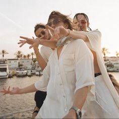 three people on a boat with their arms in the air and one person wearing sunglasses