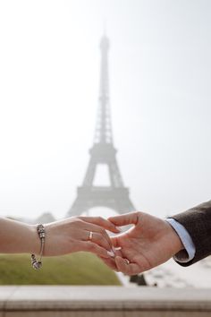 two people holding hands in front of the eiffel tower