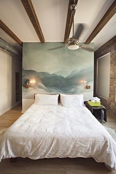 a bedroom with a large painting on the wall above the bed and ceiling fan in front of it