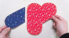 two handmade heart shaped magnets being held by someone's hands on a white surface