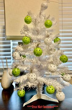 a white christmas tree decorated with green and white ornaments