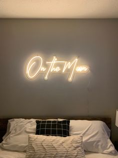 the neon sign above the bed reads, on the moon and is lit up in white