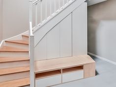 an empty room with some stairs and storage under the bannister in front of it