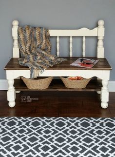 a white bench with baskets on it in front of a gray wall and black and white rug