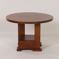 a round wooden table sitting on top of a white floor