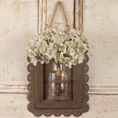 a vase filled with white flowers sitting on top of a wooden frame