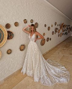 a woman in a wedding dress leaning against a wall with plates on the wall behind her