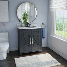 a white toilet sitting next to a bathroom sink under a round mirror on top of a wooden cabinet