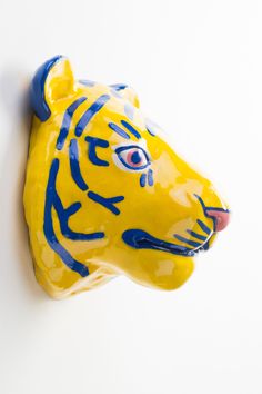 a yellow and blue ceramic tiger head mounted on a wall