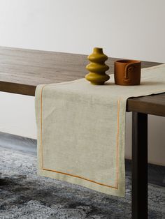 a wooden table topped with a brown vase and a white cloth on top of it