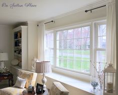 a living room filled with furniture next to a window covered in white curtains and drapes