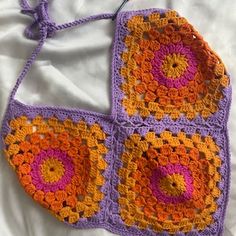 an orange and purple crocheted bag on a bed