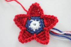 a red white and blue crocheted star ornament on a white surface