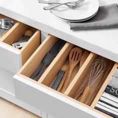 an open drawer with utensils and spoons in it on a counter top