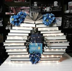 a stack of books sitting on top of a table covered in blue flowers and lights