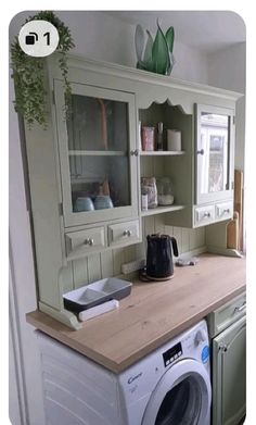 a washer and dryer sitting in a kitchen next to a cabinet with glass doors