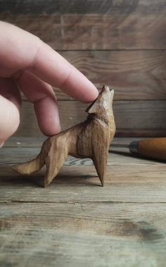 a hand holding a small wooden toy dog