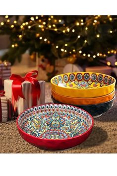 three bowls are sitting next to each other on the floor with presents in front of them