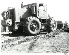 an old black and white photo of a large truck in the middle of a dirt field